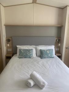 uma cama branca com duas almofadas e uma toalha branca em Feorag Lodge em Aviemore