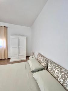 Camera bianca con divano e parete bianca. di Monolocale Cora a Corsano