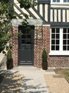 a brick house with a black door and two plants at Les pommiers in Honfleur
