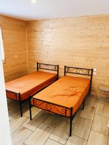 two beds in a room with wooden walls at Chaletdesilles MAYOTTE IIIII in Prat-et-Bonrepaux