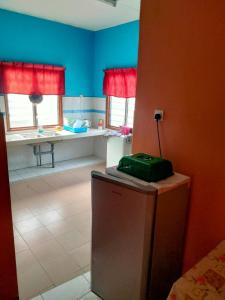 una cocina con paredes azules, ventanas rojas y una maleta verde en HOMESTAY CAHAYA PUTERI, en Tangga Batu