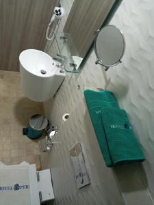 a bathroom with a sink and a mirror and green towels at Hôtel La Perla in Al Hoceïma