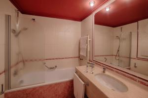 a bathroom with a tub, sink, mirror and bathtub at Bellavista Relax Hotel in Levico Terme
