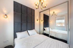 1 Schlafzimmer mit 2 Betten und einem Spiegel in der Unterkunft Nowa Praga Geometric Yellow Apartment in Warschau
