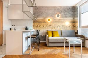 eine Küche und ein Wohnzimmer mit einem Sofa und einem Tisch in der Unterkunft Nowa Praga Geometric Yellow Apartment in Warschau