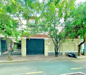 une maison jaune avec un garage bleu dans l'établissement Gem Villa 15, biệt thự 8 phòng ngủ lớn, hồ bơi lớn, à Hô-Chi-Minh-Ville