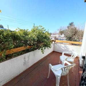 2 sillas blancas en un balcón con plantas en Del Sol en General Rodríguez