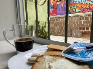 einen Teller mit Brot und eine Tasse Kaffee und ein Glas Kaffee in der Unterkunft Barra Porto - Suítes & Kitnets in Salvador