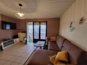 uma sala de estar com um sofá e uma mesa em DL LES 4 SAISONS - Meublé Tourisme 3 Etoiles em Brive-la-Gaillarde
