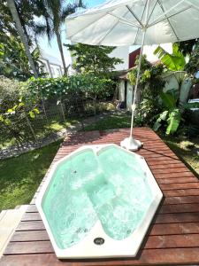 bañera de hidromasaje con sombrilla en una terraza de madera en Casa Serra e Mar - Novo Campeche, en Florianópolis