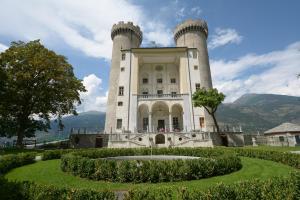 a building with two towers with a garden in front at Chez Orsille in Aymavilles