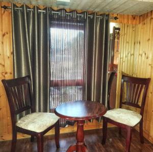 a table and two chairs in front of a window at Dreamhome Stay in Kurseong