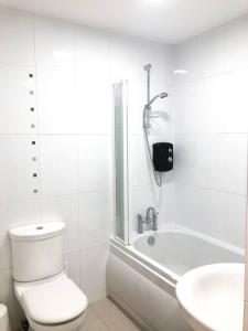 a bathroom with a toilet and a tub and a sink at Light & Spacious Loch Lomond Apartment in Alexandria