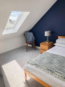 a bedroom with a bed and a chair and a window at Light & Spacious Loch Lomond Apartment in Alexandria