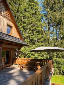 une terrasse en bois avec des bancs et un parasol dans l'établissement Chata na přehradě s vlastním wellness, à Horní Bečva