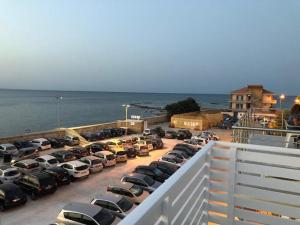 un estacionamiento lleno de autos estacionados al lado del océano en Sea House en Marzamemi
