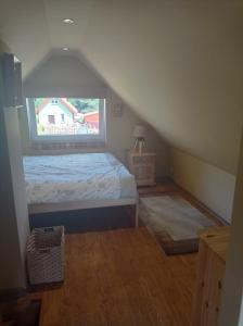 a attic bedroom with a bed and a window at Zielona Chatka pod Srebrnym Żurawiem in Wydminy