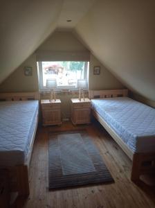 two beds in a attic room with two windows at Zielona Chatka pod Srebrnym Żurawiem in Wydminy