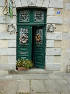 zielone drzwi na budynku z dwoma doniczkami w obiekcie La Maison de Claire w mieście Val Couesnon