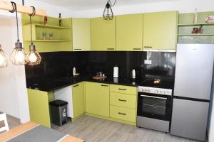 une cuisine avec des armoires jaunes et des comptoirs noirs dans l'établissement Apartment Sarajlic, à Prijedor