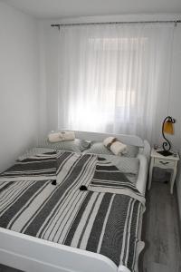 a white bedroom with a bed with a striped blanket at Apartment Sarajlic in Prijedor