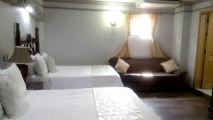 een hotelkamer met 2 bedden en een bank bij Hotel Hacienda los Narcisos in San Juan de los Lagos