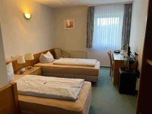 a hotel room with two beds and a desk at Niebuhrs Hotel in Friedrichsdorf