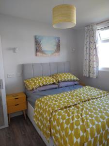 a bedroom with a bed with a yellow and white comforter at Sandy Toes 435 Norton Park Dartmouth in Dartmouth