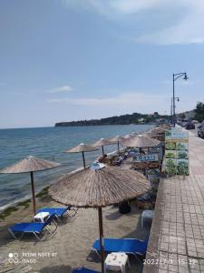 a beach with umbrellas and chairs and the ocean at Long Beach Apartment in Makrygialos