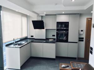 una cocina con armarios blancos y encimeras negras en Apartamento Rosario 2 en Vigo