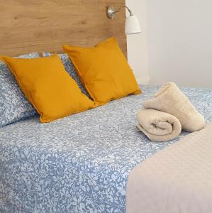 a bed with yellow pillows and a towel on it at Road Sierra 95 Habitación privada con baño y zona de cocina in Granada