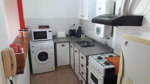 a small kitchen with a washing machine and a microwave at Espacio C Av Poeta Lugones GRAN VISTA in Córdoba