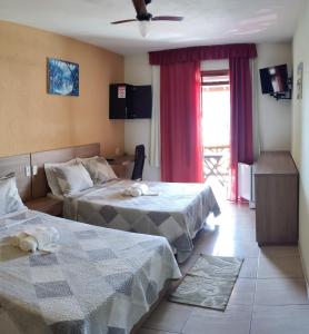 a hotel room with two beds and a window at Pousada Tropicalia in Itaparica Town