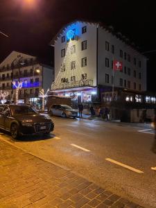 Sendy Home Roccaraso 1 في روكاراسو: شارع المدينة بالليل فيه عمارة فيها شجرة عيد الميلاد