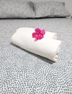 a white towel with a pink flower on a bed at Holiday home Mennulita in Lipari