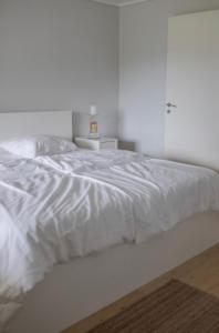 a white bed in a white bedroom with a table at Jåsund SunView in Lyngdal