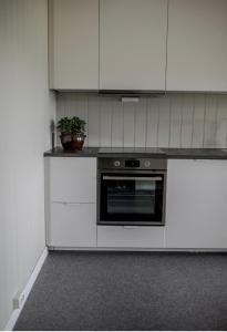 a kitchen with white cabinets and a black oven at Jåsund SunView in Lyngdal