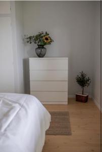 Un dormitorio con una cama y un jarrón de flores en un tocador en Jåsund SunView, en Lyngdal