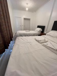 two beds in a room with white sheets at Spacious Entire Flat, 1 in Great Yarmouth