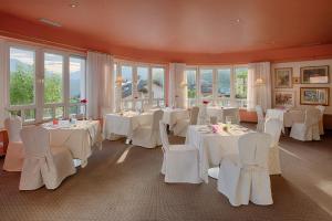a dining room with white tables and chairs and windows at Bellavista Relax Hotel in Levico Terme