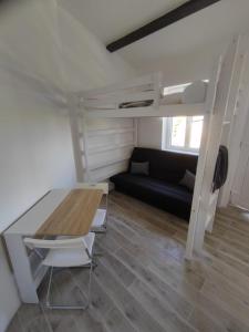 Habitación con litera, mesa y sofá. en Petit gîte de charme Bichta Eder en Magnac-Lavalette