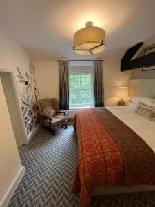 a bedroom with a bed and a chair and a window at Royal Oak Hotel in Rosthwaite