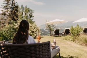 Eine Frau, die auf einem Stuhl mit einem Glas Wein sitzt. in der Unterkunft Gut Berg Naturhotel in St. Johann im Pongau