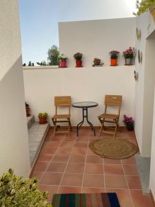 un patio con mesa, sillas y plantas en Alojamientos Tía María en Fernán Pérez