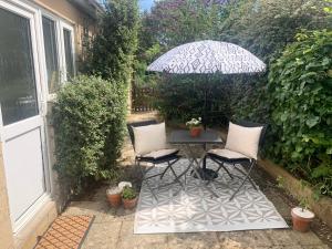 a patio table with two chairs and an umbrella at Penderels, Willersey in Broadway