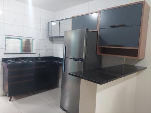 a kitchen with a stainless steel refrigerator and a sink at Casa Arembepe em frente as piscinas naturais in Arembepe