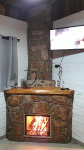 una chimenea de piedra con TV encima. en Chalé Riacho Frio, en Gonçalves