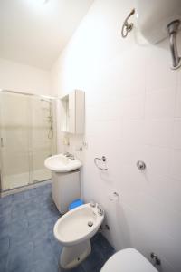 La salle de bains blanche est pourvue de toilettes et d'un lavabo. dans l'établissement Petracuzza casa vacanze, à Tortora