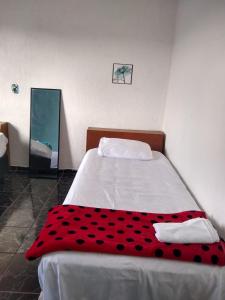 a red and black blanket on a bed in a room at Casa de praia em Itanhaem in Itanhaém