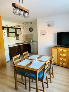 a dining room with a table and chairs and a kitchen at Apartament Morski in Jarosławiec